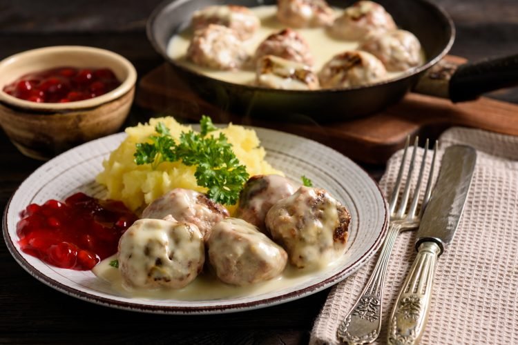 Festive holiday feast platter with Swedish meatballs, rosemary sprigs, lingonberry sauce, and roasted sides