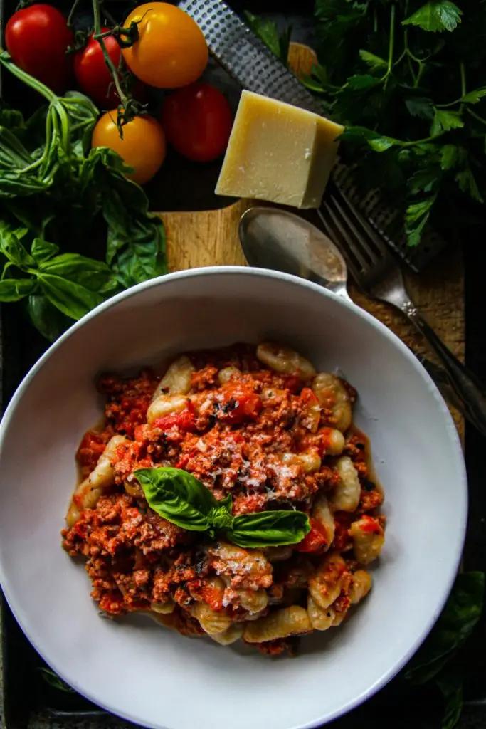 Fluffy gnocchi bathed in rich bolognese sauce, topped with Parmesan and herbs