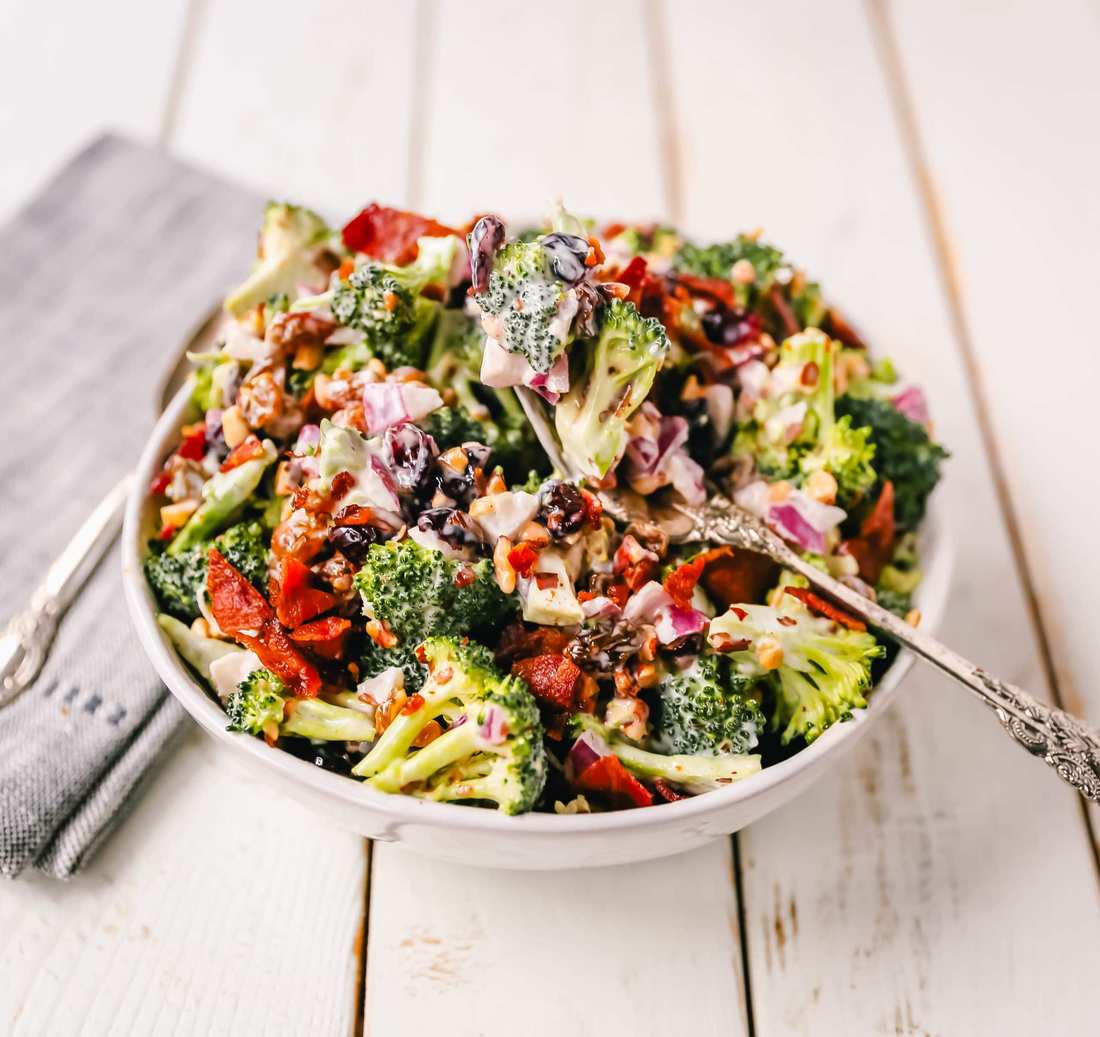 Classic broccoli salad featuring crisp florets, creamy dressing, sunflower seeds, dried cranberries, shaved parmesan