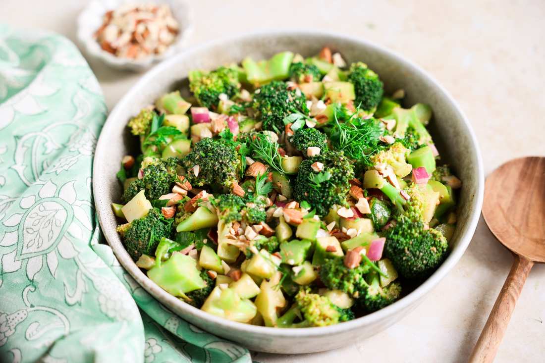 Vegan broccoli salad with florets, apple cider vinaigrette, toasted pecans, golden raisins, and vegan cheese shavings