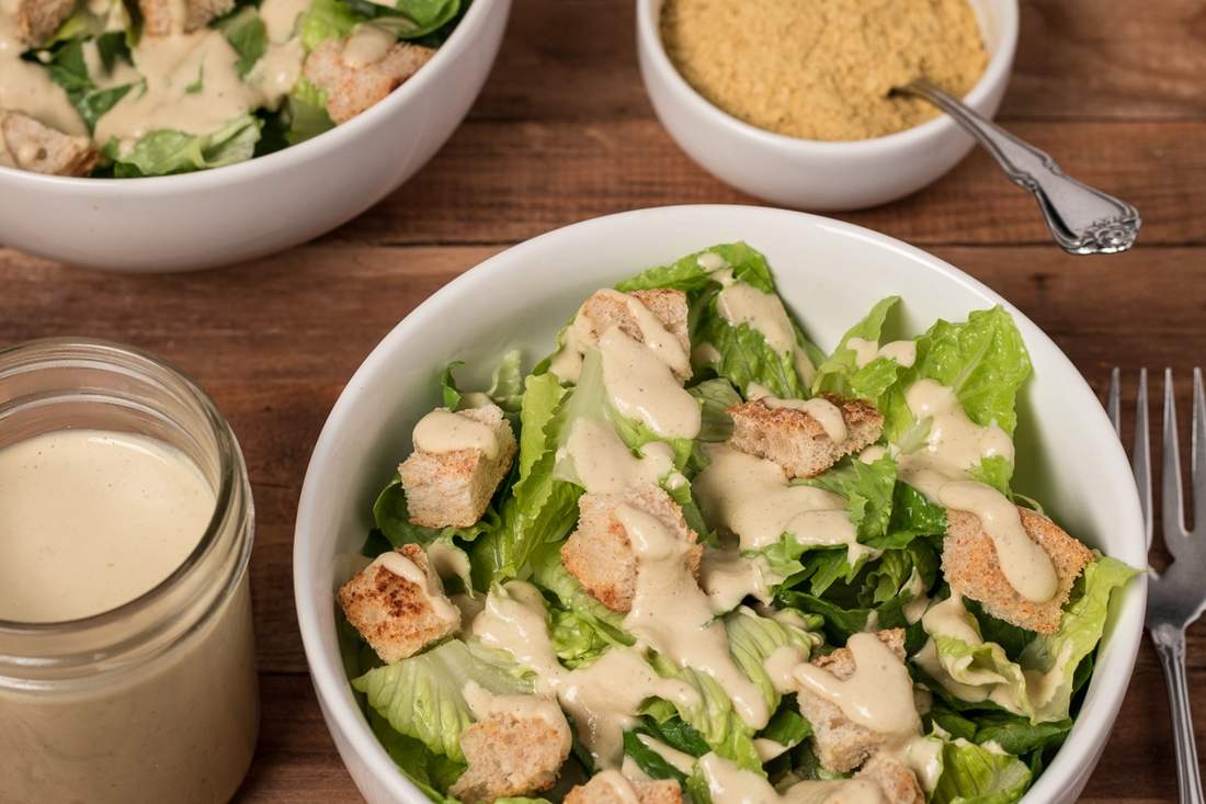 Creamy vegan caesar salad tossed with crisp romaine, crunchy croutons, shaved parmesan, and creamy dressing.