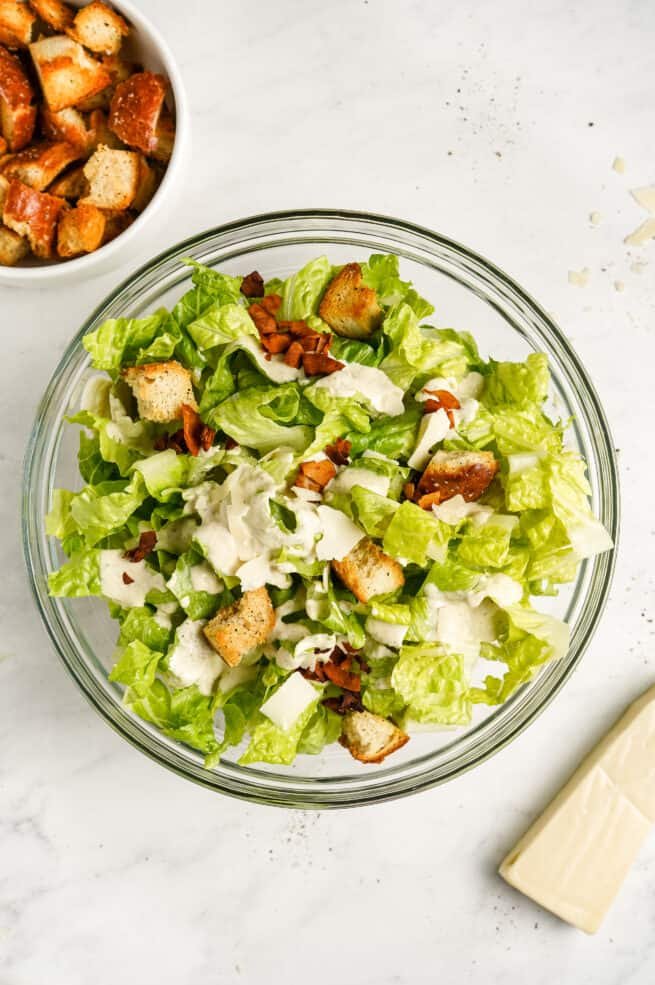 Homemade vegan caesar salad featuring crisp romaine, crunchy croutons, shaved parmesan, and creamy dressing.