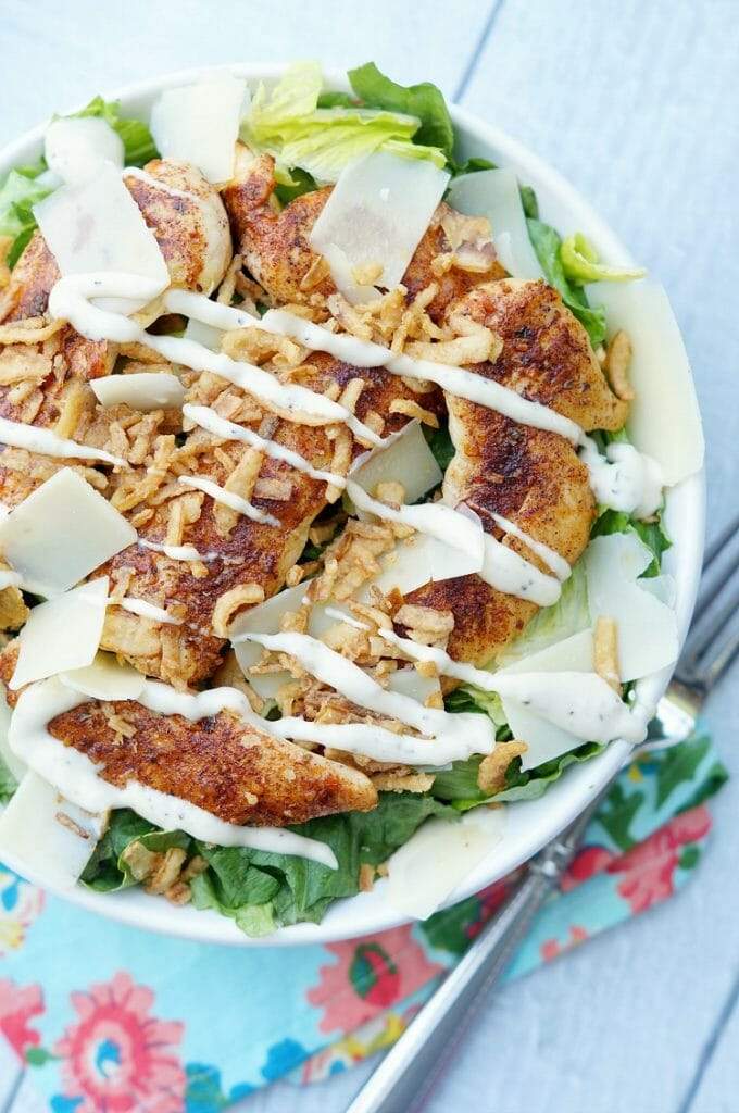 Zesty blackened chicken caesar salad featuring crisp romaine, crunchy croutons, shaved parmesan, creamy dressing.