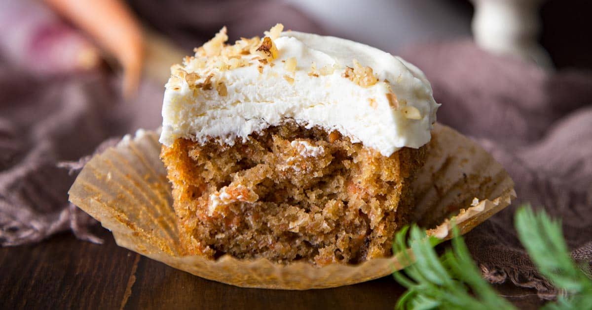 Elegant carrot cupcake crowned with a delicate cream cheese rose and a sprinkle of powdered sugar