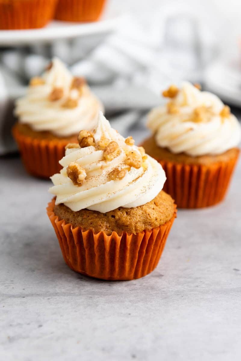 Classic carrot cupcakes topped with cream cheese frosting and decorative butter‑cream carrot accents