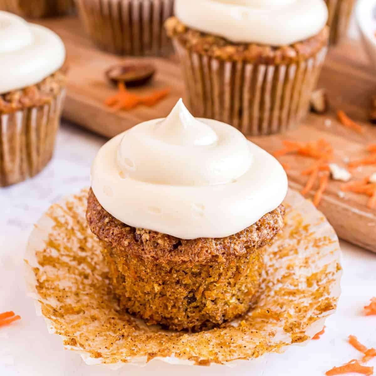 Elegant carrot cupcake topped with a delicate cream cheese frosting rose and a sprinkle of cinnamon