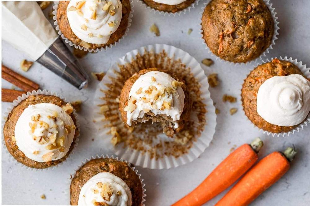Lightened carrot cake muffins topped with a thin swirl of cream cheese frosting and a dusting of cinnamon