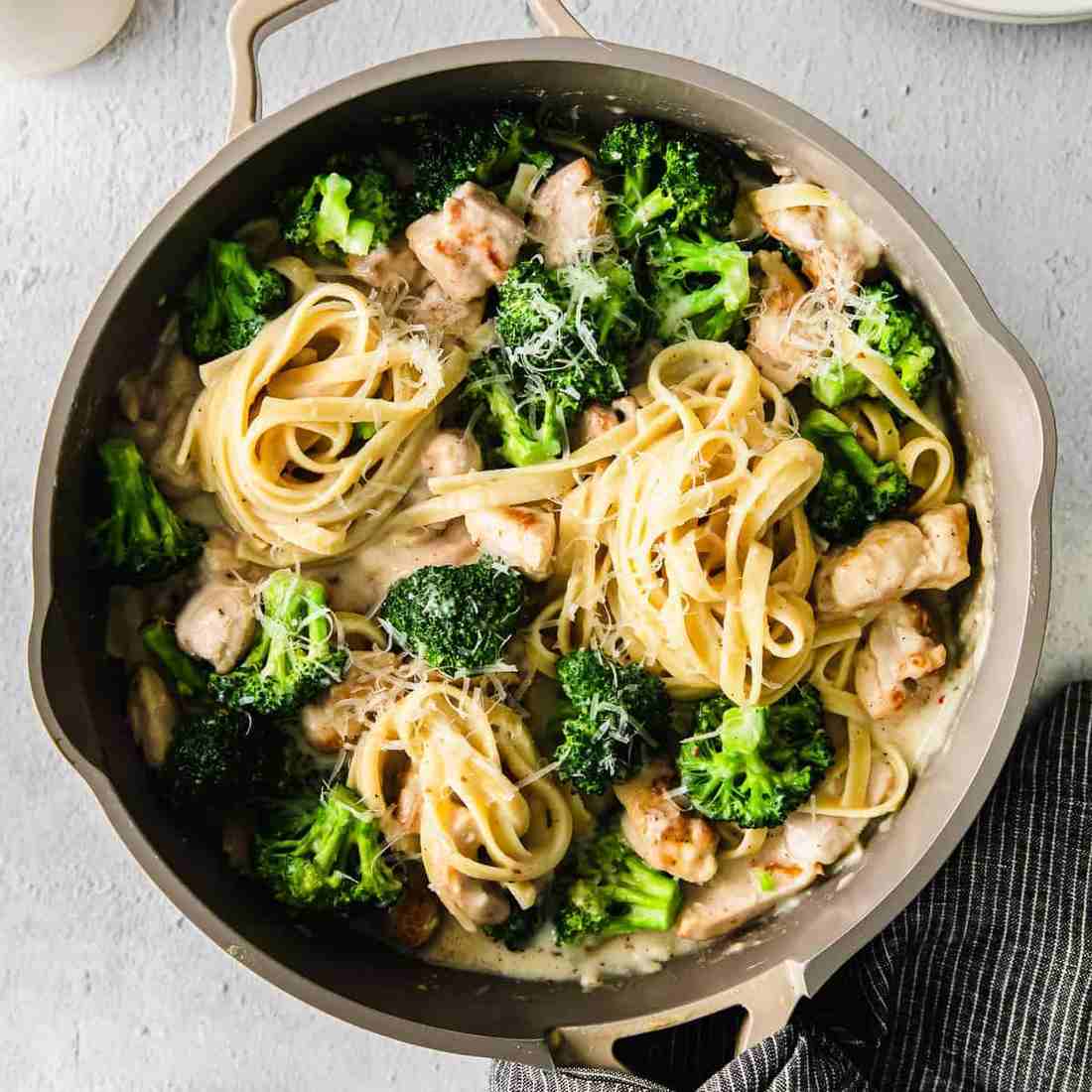 Chicken alfredo with broccoli featuring tender chicken cutlets, silky parmesan cream sauce, and twisted fettuccine.