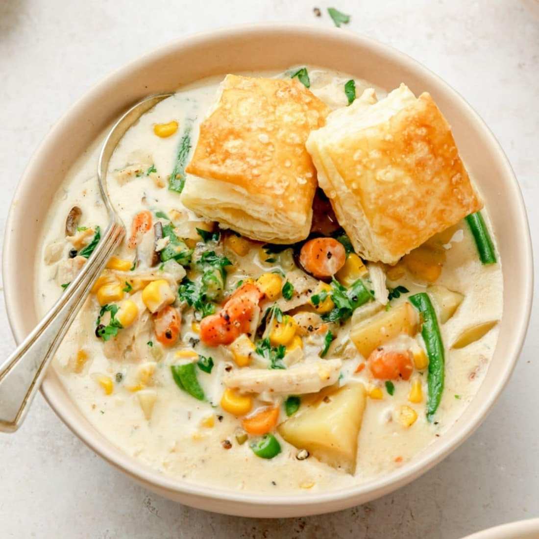 Classic creamy chicken pot pie soup with tender chicken, peas, carrots, potatoes, and flaky pastry topping