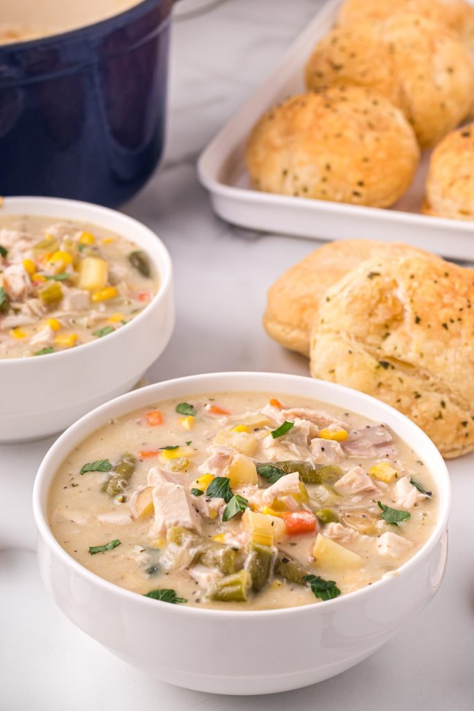 Classic creamy chicken pot pie soup with tender chicken, carrots, peas, potatoes, and a flaky biscuit topping