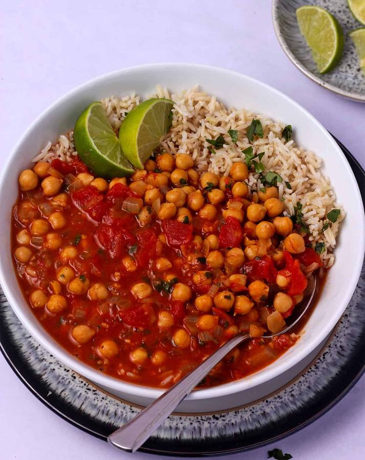 Creamy coconut chickpea curry with a bright orange sauce, fresh cilantro, and lime, served over jasmine rice.