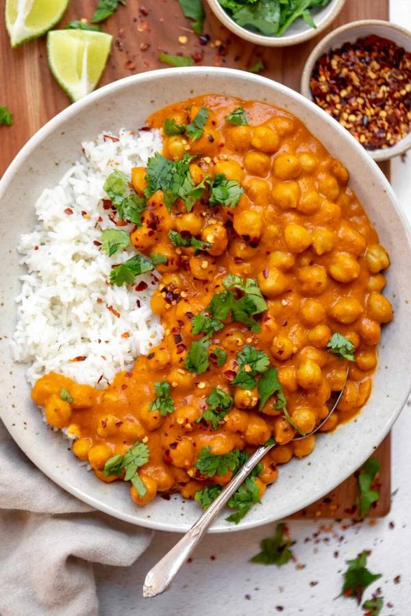 Vibrant Thai red chickpea curry simmering in rich coconut sauce topped with fresh cilantro and lime.