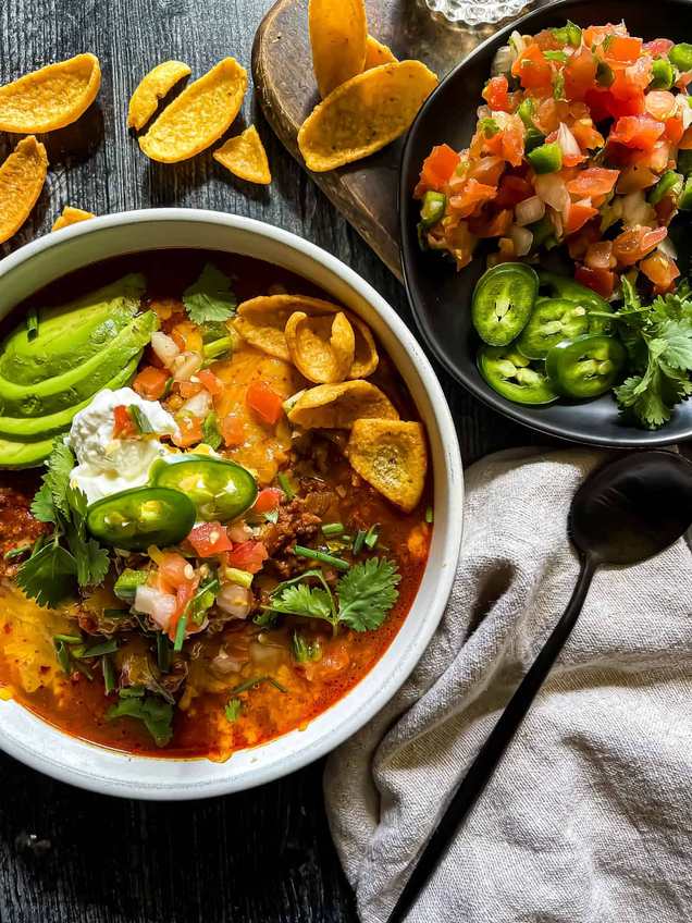 Sweet heat ancho beef chili topped with diced onions and sour cream in a white bowl