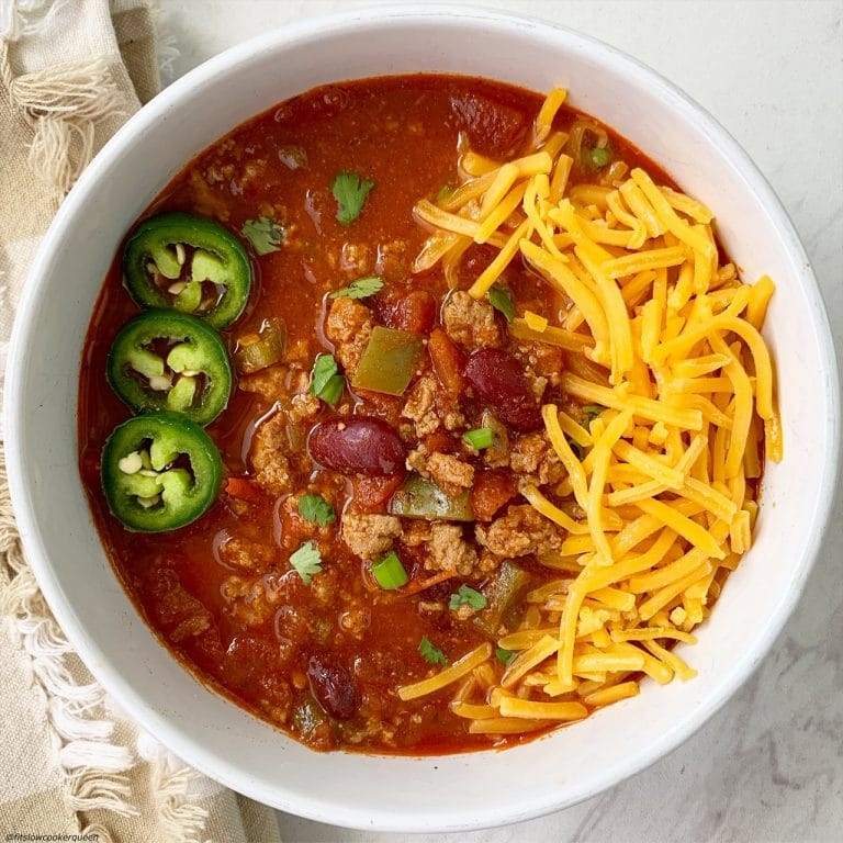 Slow cooker sweet potato turkey chili topped with sour cream in a warm ceramic crock