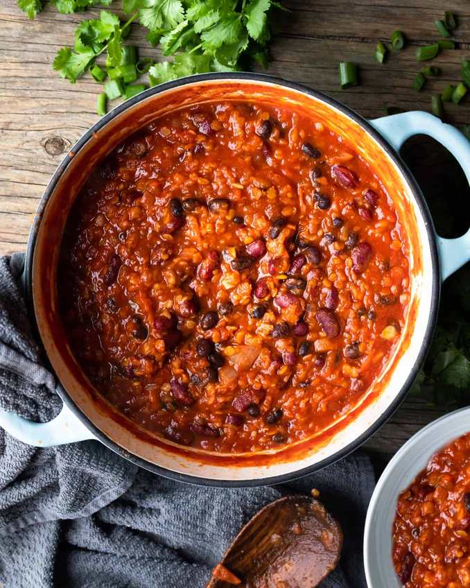 Hearty brown lentil and sweet corn vegetarian chili garnished with fresh cilantro