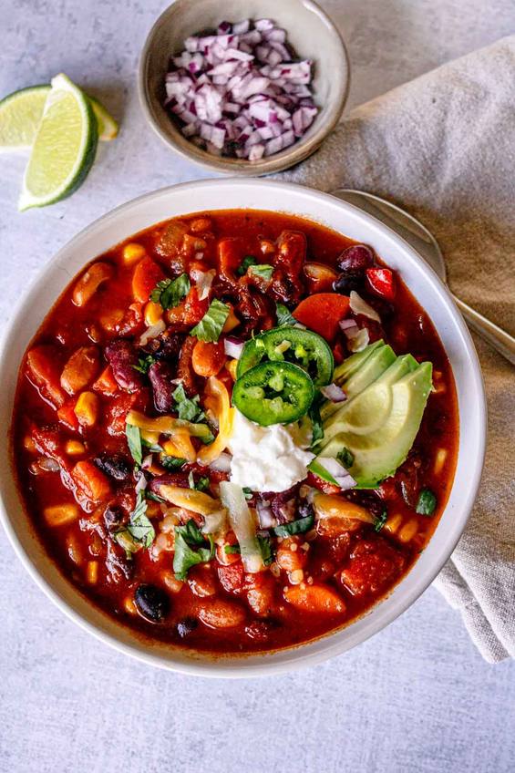 Spicy cocoa black bean chili in a dark bowl with sour cream and jalapeño slices