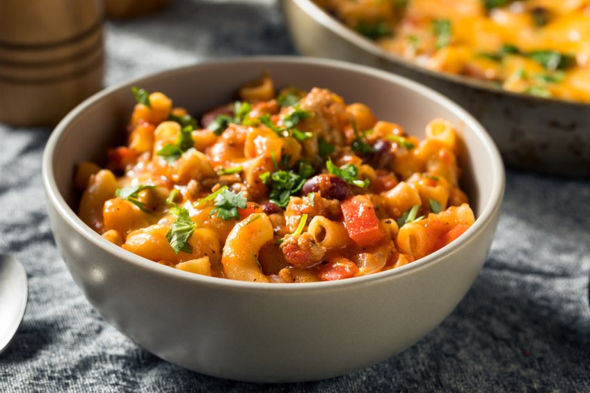 Steamy bowl of cheesy chili mac with beef, beans, melted cheese, sour cream, jalapenos