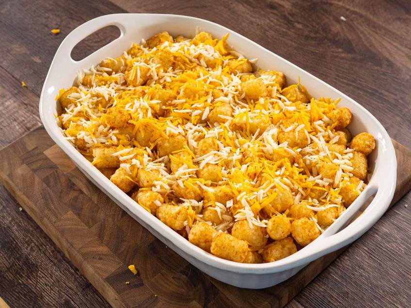Baked chili tater tot casserole with beef, beans, melted cheese, sour cream, jalapenos, golden tots