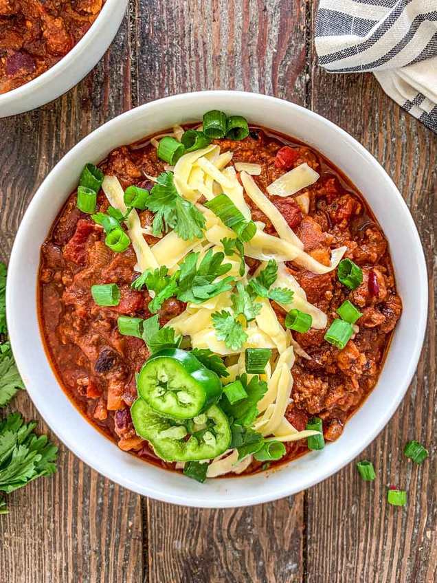 Dutch oven beef chili with beans, melted cheese, sour cream, jalapenos, cocoa‑chipotle depth
