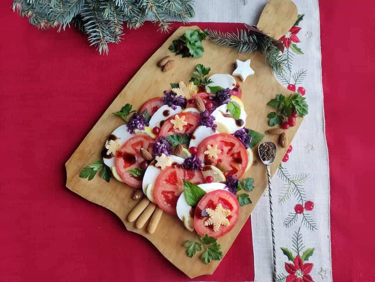 Fresh mozzarella, cherry tomatoes, and basil arranged as a green Christmas tree on a wooden board