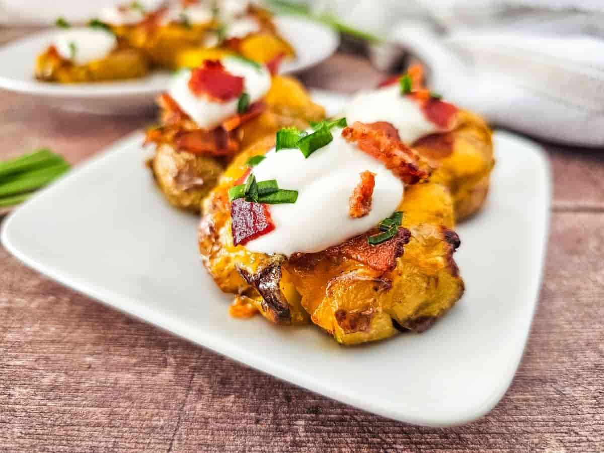 Crispy smashed potatoes topped with sour cream, bacon bits, chives, and shredded cheese