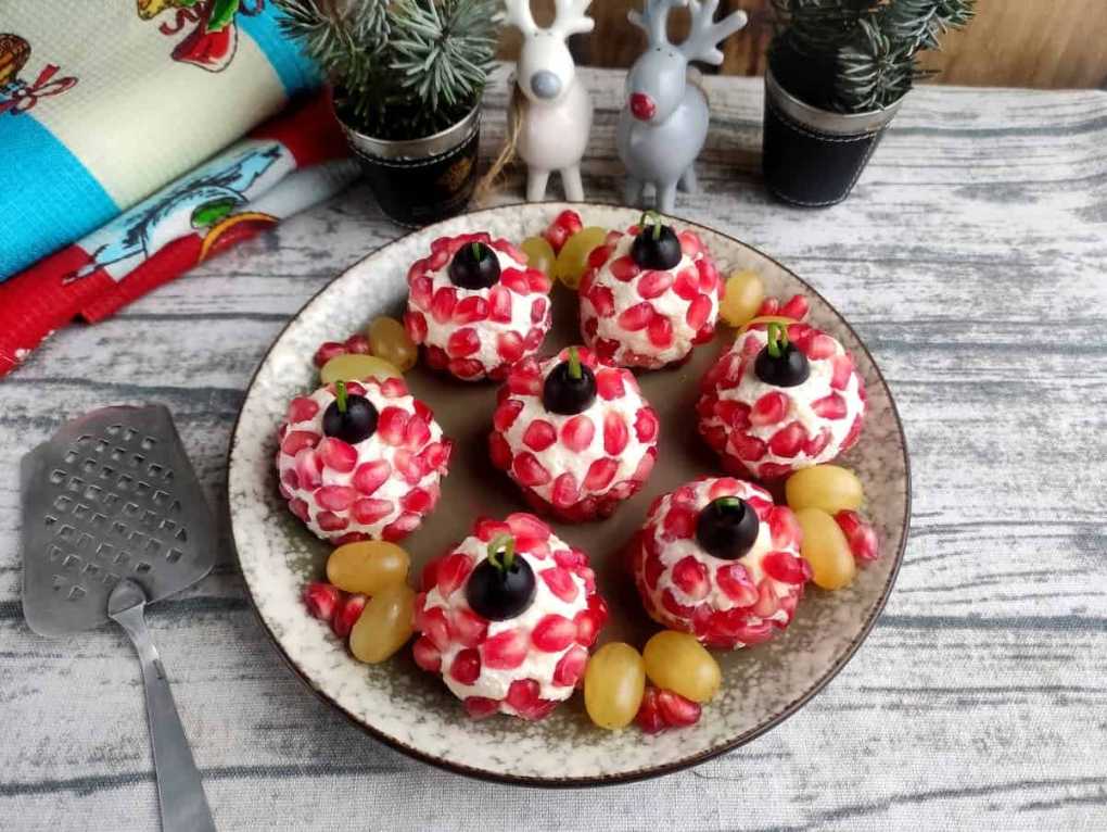 Red‑glazed cheese balls decorated with pomegranate seeds and rosemary, resembling ornaments