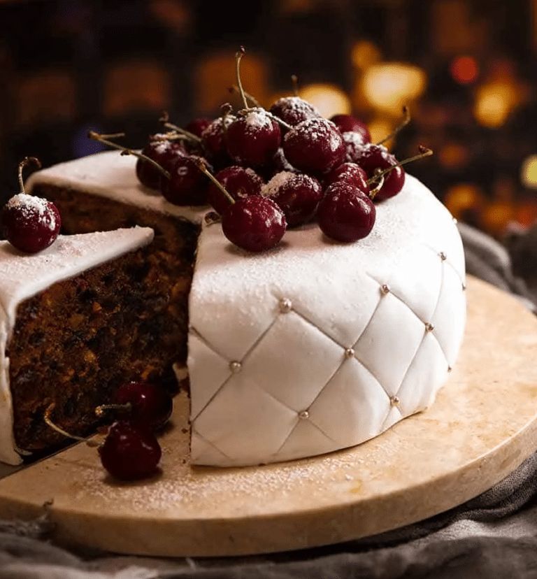 Dark fruitcake covered in smooth fondant, drizzled with glossy cherry glaze