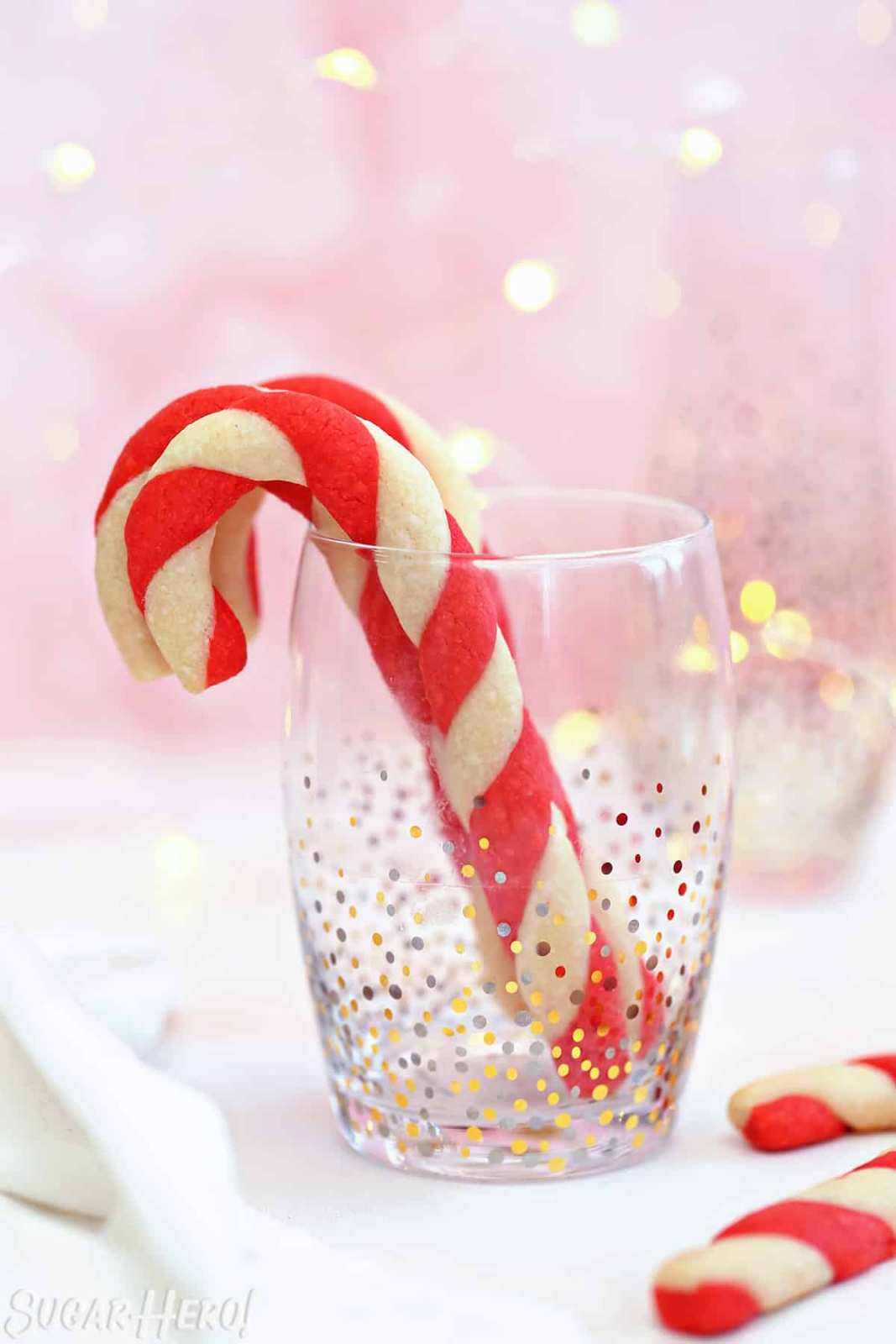 Red and white striped sugar cookies twisted into spirals, dusted with powdered sugar on a white plate.