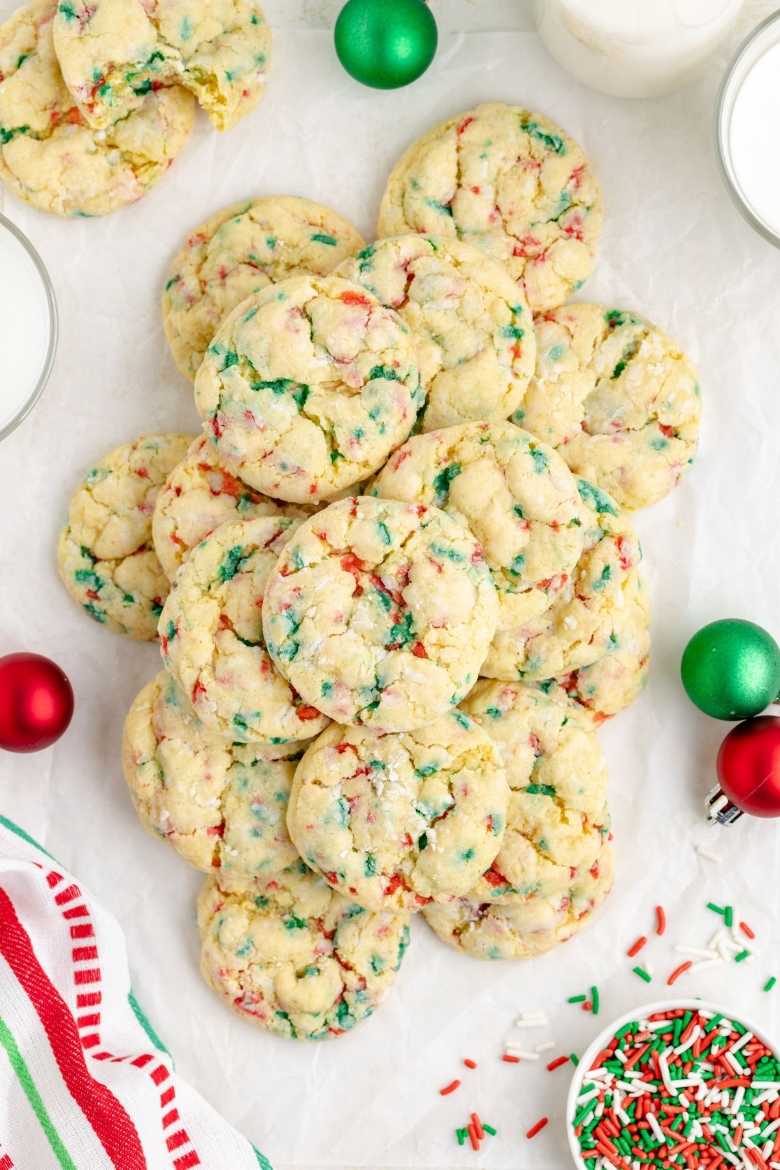 Round sugar cookies filled with colorful sprinkles, looking soft and chewy on a baking sheet.