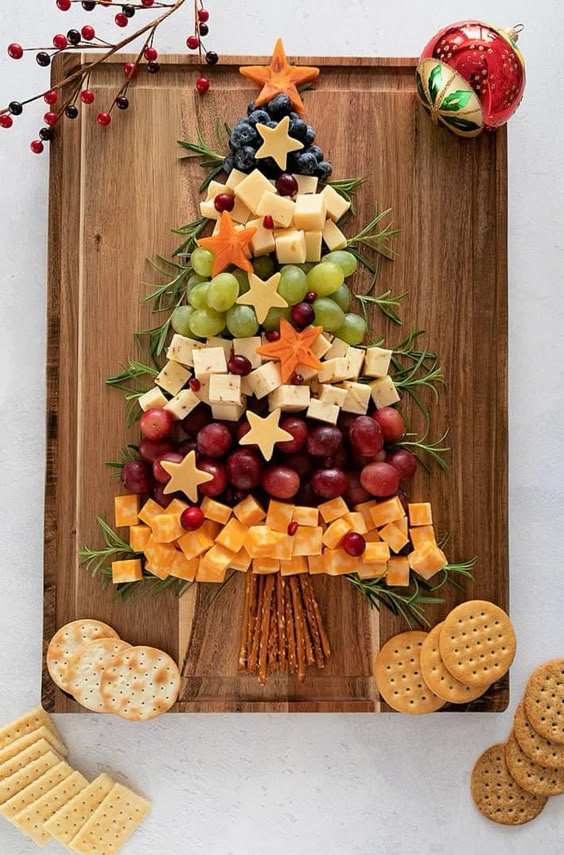 Green grape “tree” made of cheese cubes, grapes, and nuts on a rustic board