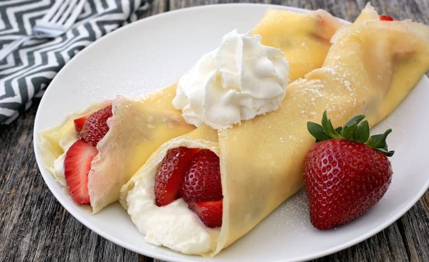 Golden thin crepes topped with airy strawberry whipped cream and fresh berry garnish