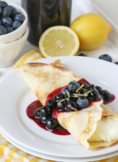 Thin golden crepes with lemon‑infused batter and juicy blueberries, finished with a dusting of powdered sugar
