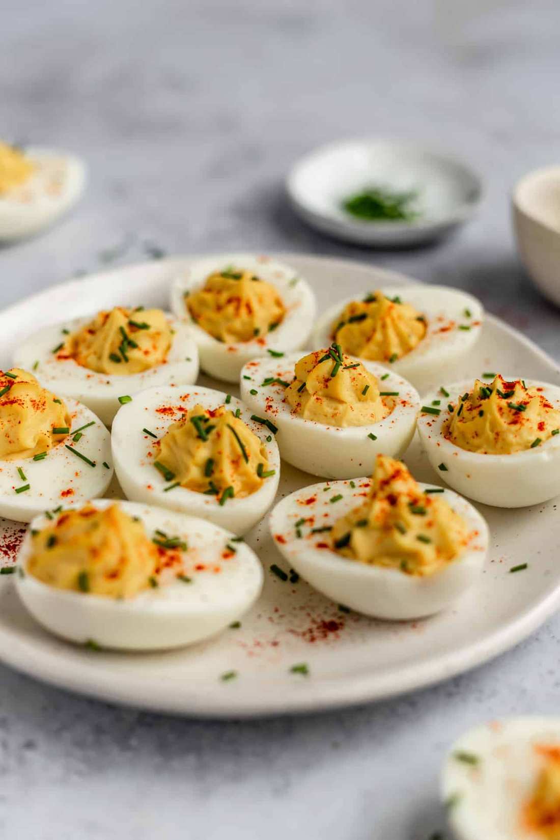 Classic deviled eggs with creamy yolk filling, smoky paprika, fresh chives, and crunchy bacon bits