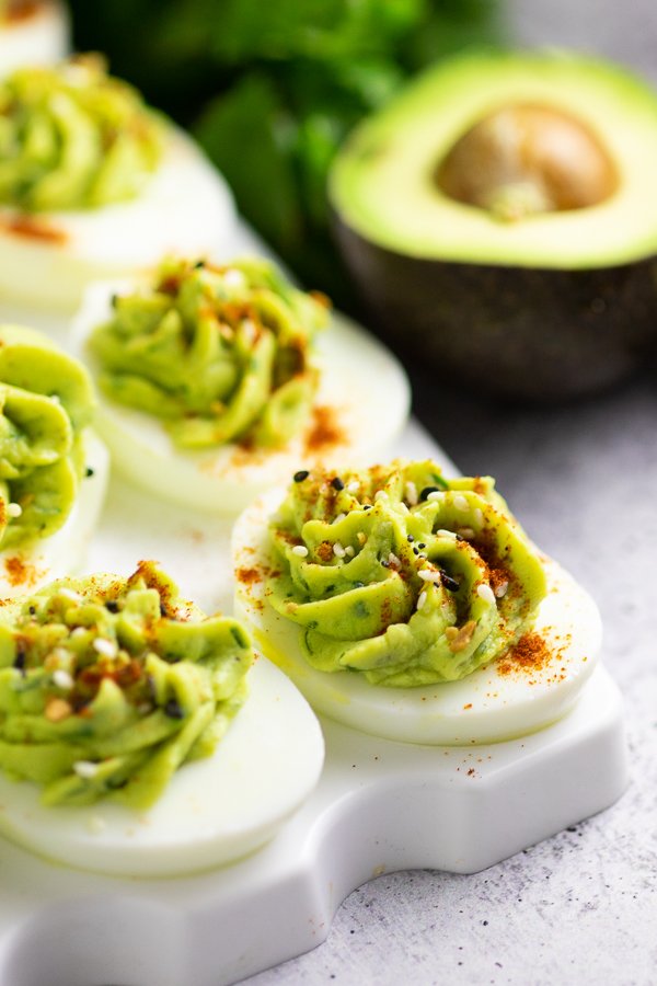 Avocado deviled eggs, silky avocado‑yolk filling, lime zest, cilantro, paprika garnish