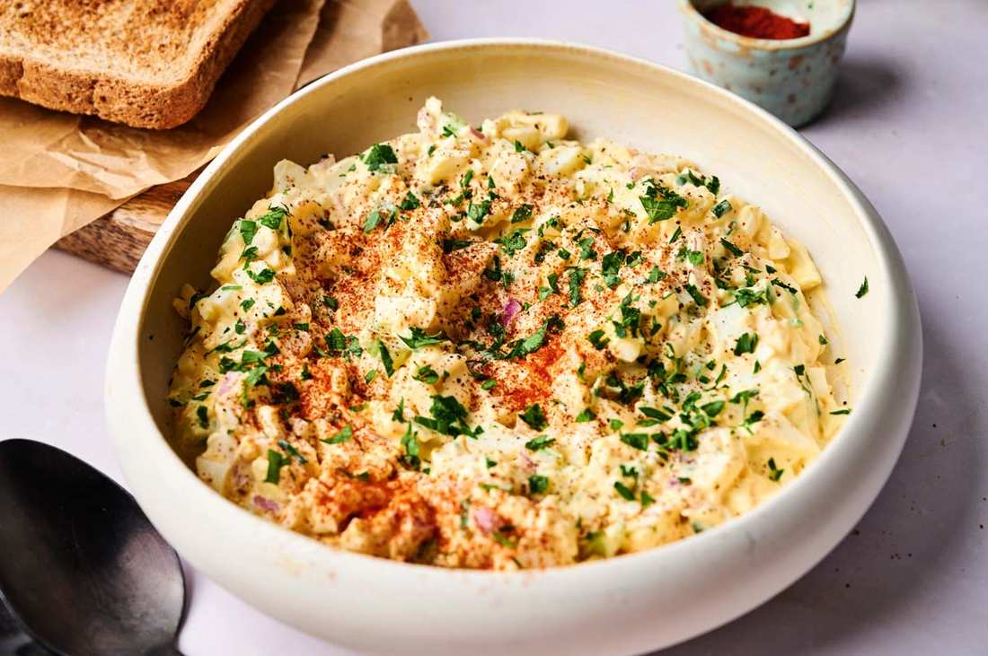 Classic creamy egg salad with chopped hard-boiled eggs, creamy mayo, fresh herbs, served as a party appetizer on a platter
