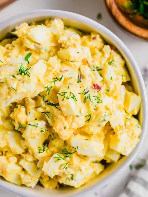 Classic creamy egg salad with chopped hard-boiled eggs, silky mayo, fresh herbs, and crunchy lettuce in a sandwich