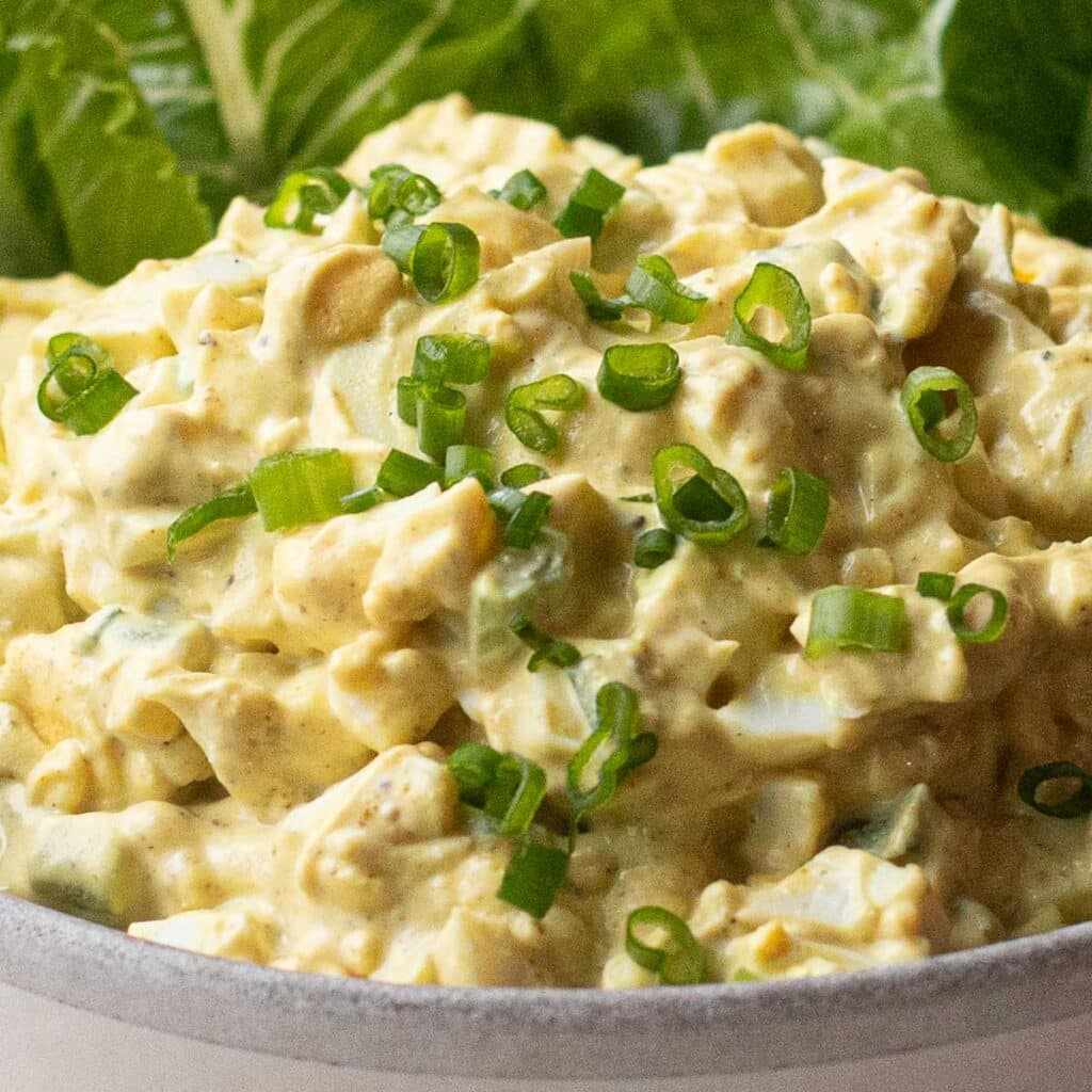 Curried egg salad with chopped hard‑boiled eggs, creamy mayo, curry powder, cilantro, and a drizzle of lime, served in a colorful bowl