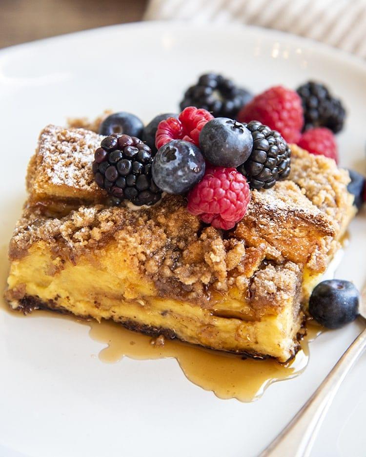 Cinnamon apple overnight French toast casserole with golden custardy bread cubes, warm apple slices, and a drizzle of maple syrup