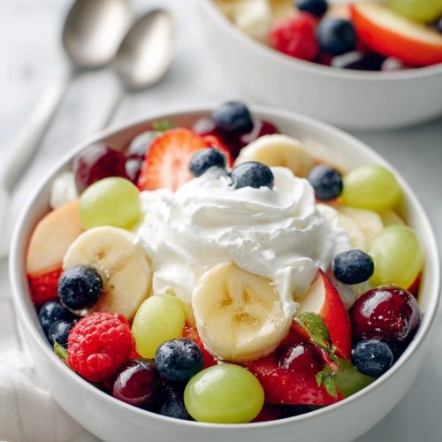 Creamy whipped fruit salad with mixed berries, banana slices, and a citrus‑honey drizzle