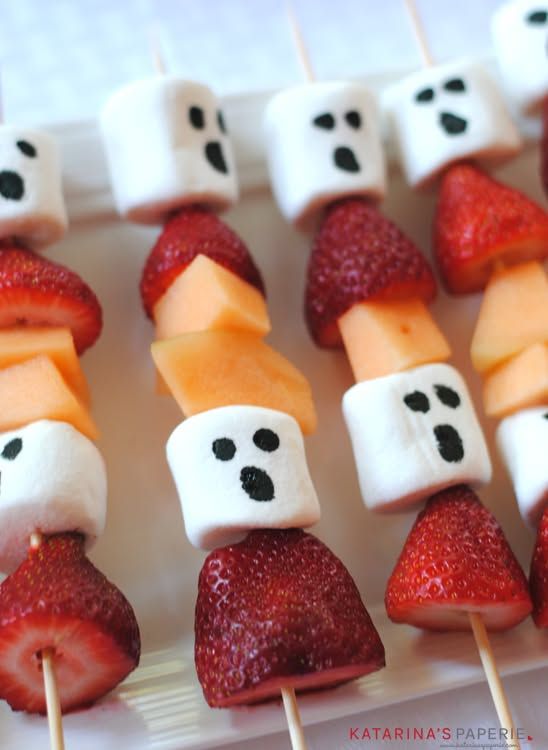 Alternating fruit and ghost-shaped marshmallows on skewers with a dusting of powdered sugar.