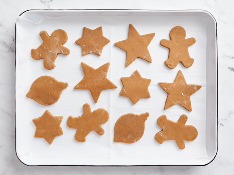 Unbaked gingerbread cut‑out cookies on a baking sheet, warm spices, festive shapes