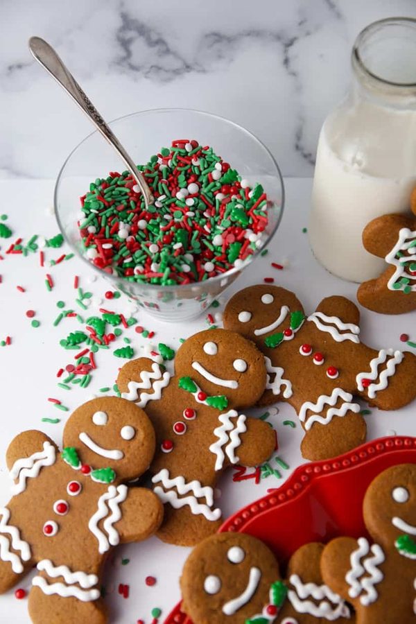 Mini gingerbread men topped with festive sprinkles, served alongside a glass of milk