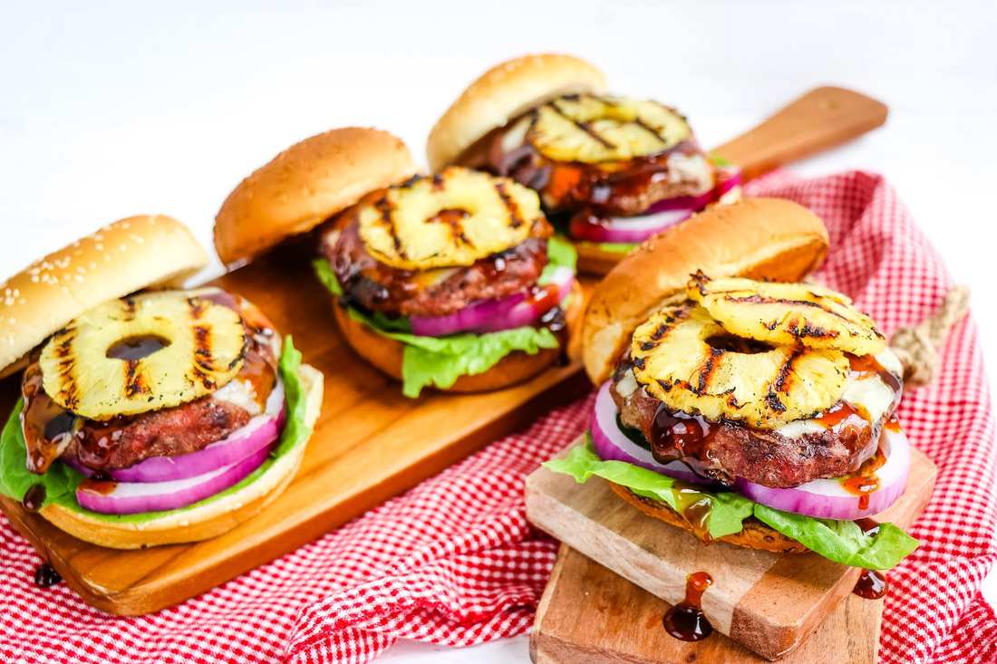 Grilled pineapple burger topping with crisp broccoli florets, tangy dressing, toasted nuts, dried fruit, cheese