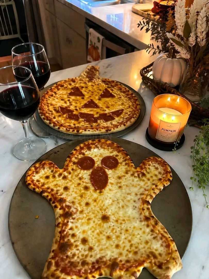 Mini pizzas shaped like ghosts and pumpkins topped with pepperoni and melted mozzarella cheese