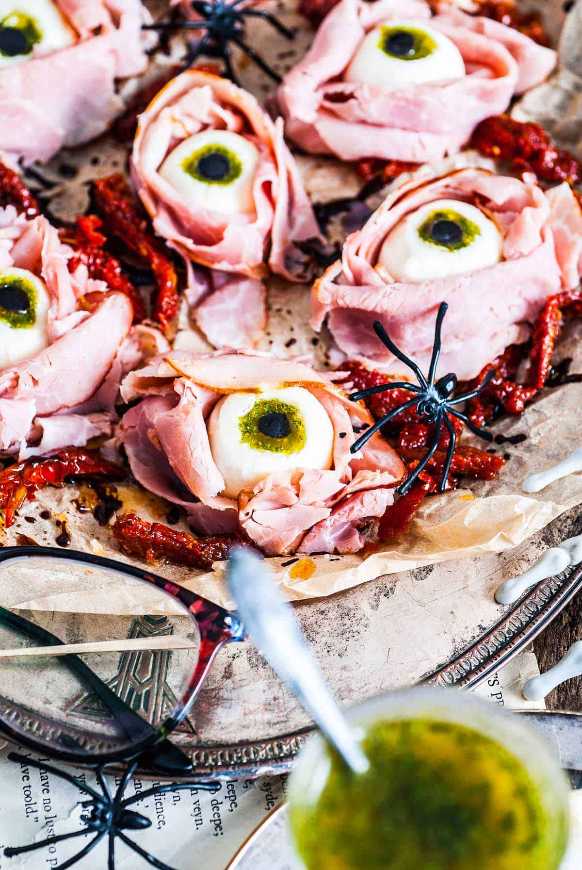 Skewered mozzarella balls, cherry tomatoes, and olive “pupils” arranged like eerie eyeballs on a platter