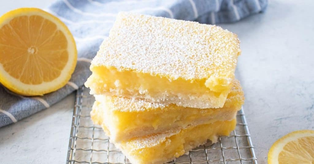 Vibrant lemon bars on a golden cashew‑butter crust, lightly powdered sugar