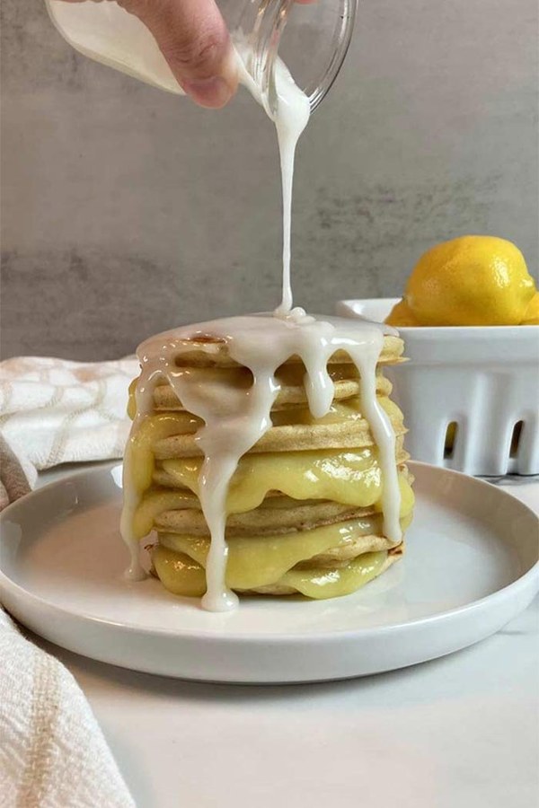Fluffy lemon pancakes drizzled with glossy lemon glaze and candied zest