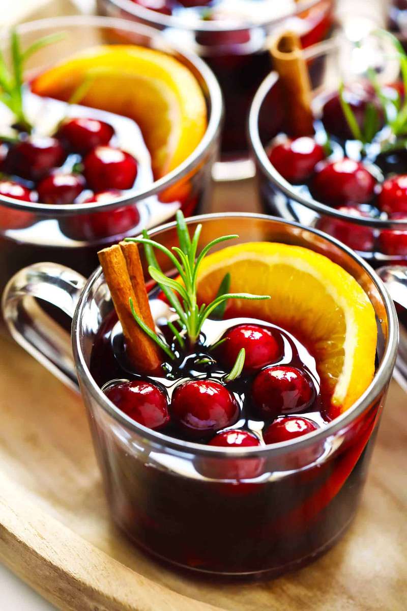 Deep crimson cranberry mulled wine with pomegranate seeds, fresh cranberries, and cinnamon stick in glass