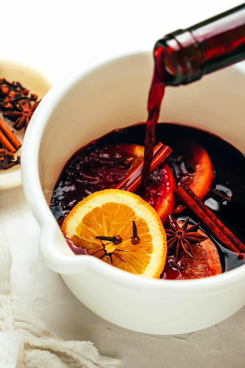 Ruby-red blood orange mulled wine with dark port, fresh orange slices, and cinnamon in glass mugs.