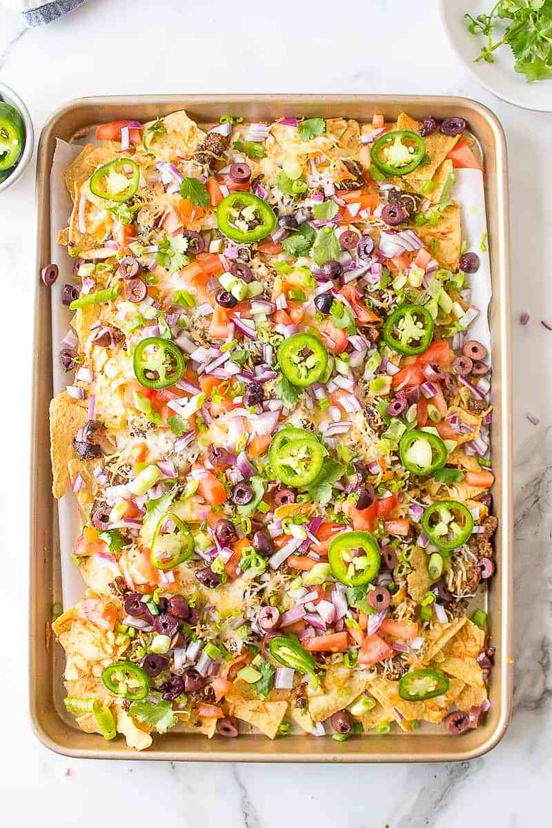 Sheet pan chorizo nachos with melted oaxaca cheese, jalapeños, creamy guacamole, and golden loaded tortilla chips